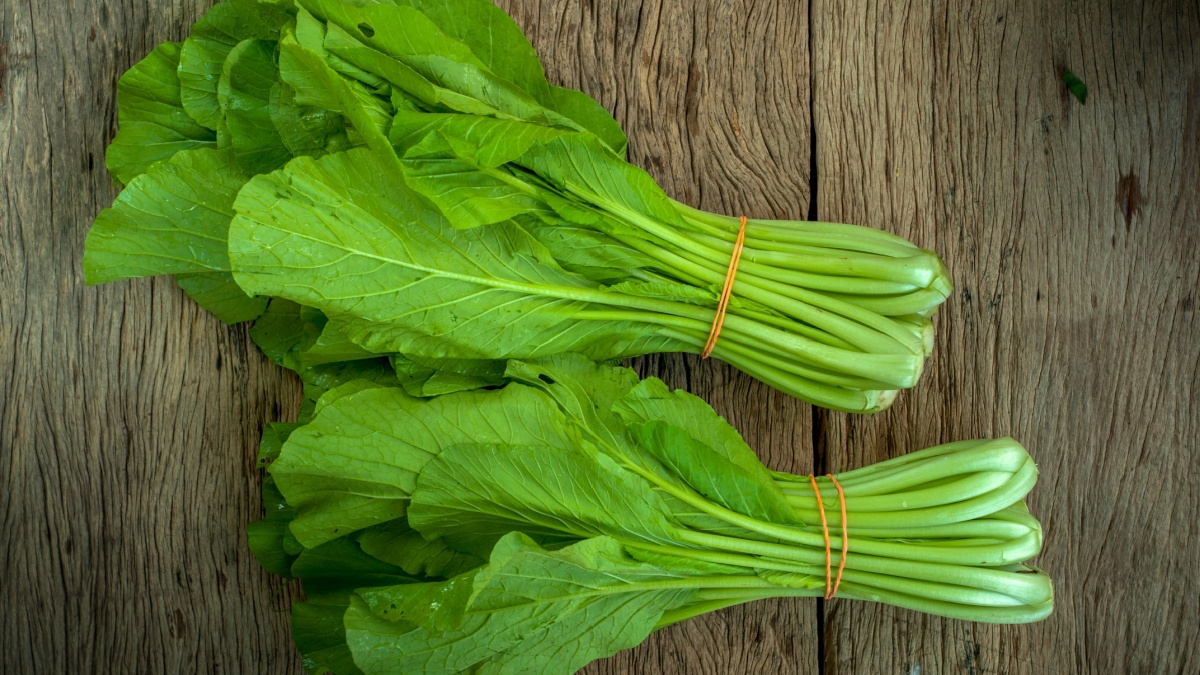 mustard greens on wooden table isolated.