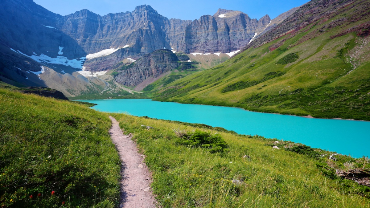 Hiking trail in beautiful alpine scenery to emerald green Cracker Lake in Glacier National Park.