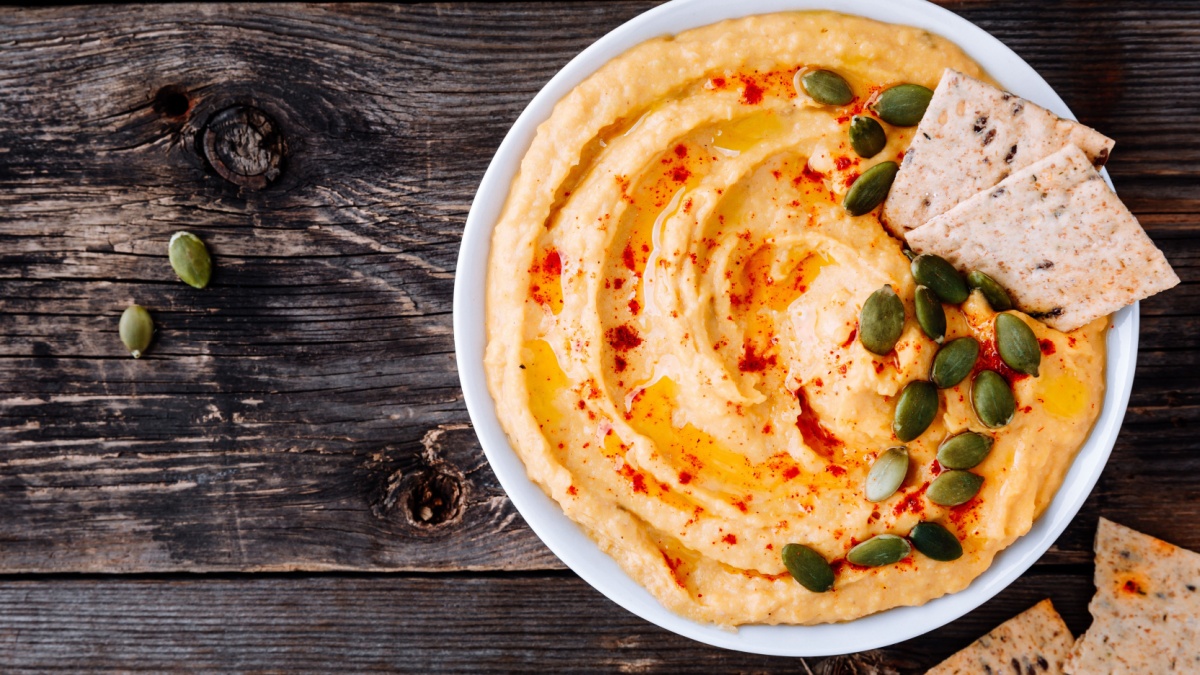 Homemade Savory Pumpkin Hummus . Thanksgiving Appetizer dip on wooden background.