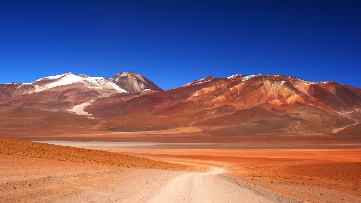 Lonely unpaved road trough Salvador Dali Desert in Altiplano, Bolivia .