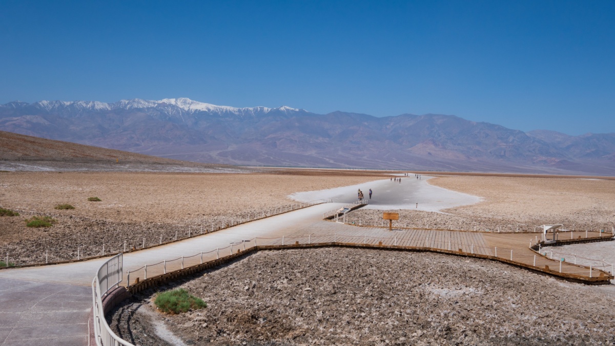 Badwater basin, Death Valley, USA. People walking out towards the lowest point. Sign post of Badwater basin in the foreground.