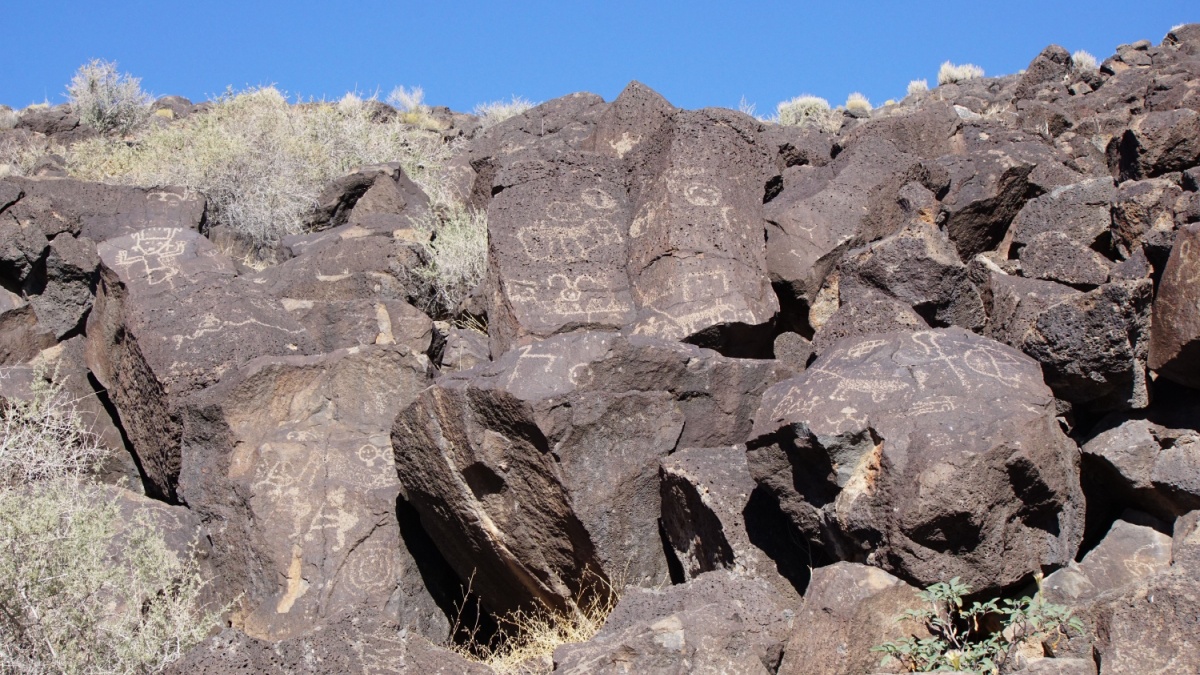 Ancient petroglyph images carved onto volcanic rocks along the Piedras Marcadas Trail at Petroglyph National Monument in Albuquerque, New Mexico.