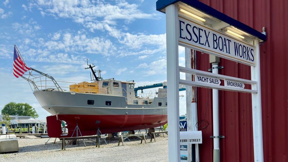 Essex, Connecticut, USA - August 13, 2023: Sign for Essex Boat Works with boat behind it. Local business along the riverfront.