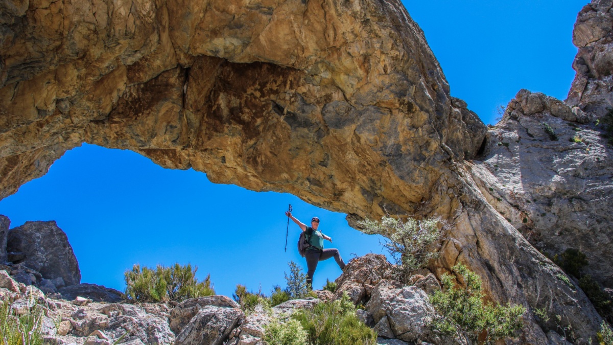 A hiker with arms open under Lexington arch in Great Basin national park. 