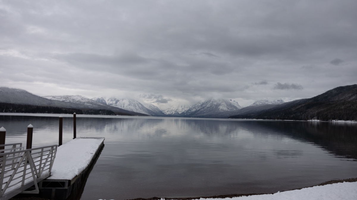 Montana lake McDonald in the national glacier park during winter with snow. Clear blue ice water with colorful stones with beautiful reflection.