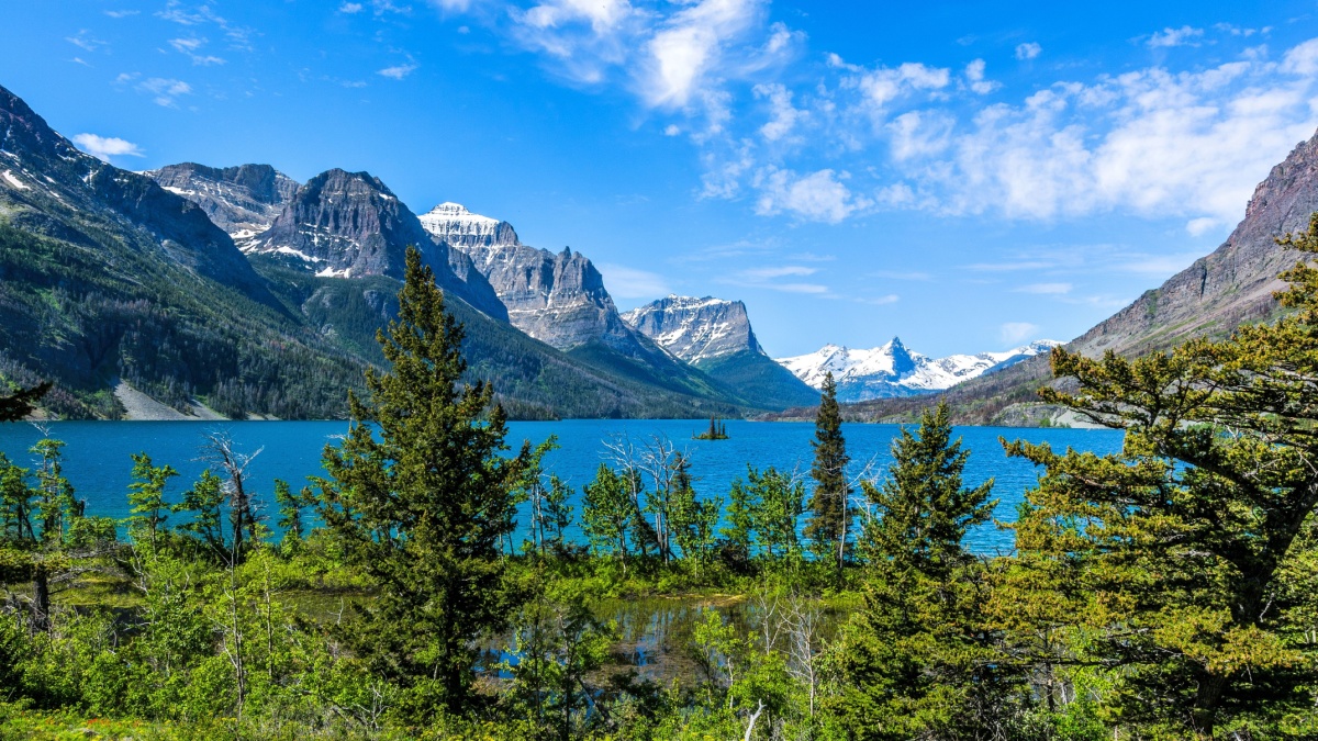 Spring at Saint Mary Lake - A panoramic view of high clouds passing over blue Saint Mary Lake and its surrounding steep mountains in Glacier National Park, Montana, USA..
