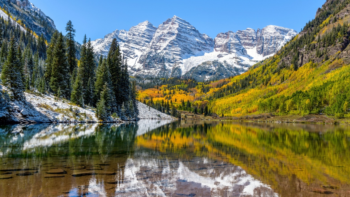 Maroon Bells and Maroon Lake - A wide-angle autumn midday view of snow coated Maroon Bells reflecting in crystal clear Maroon Lake, Aspen, Colorado, USA.