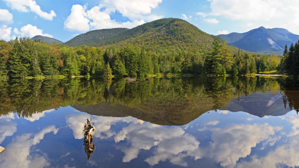 Panoramic view of Phelps Mt, Mt Marcy and Mt. Colden reflected in Marcy Dam Pond in the High Peaks region of the Adirondack Mountains of New York.