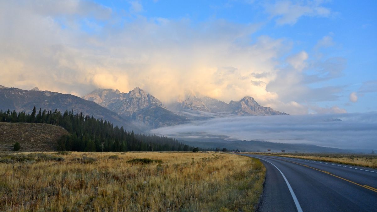 Fog rolling into Grand Teton's Gros Ventre with sun illuminating clouds in the sky.