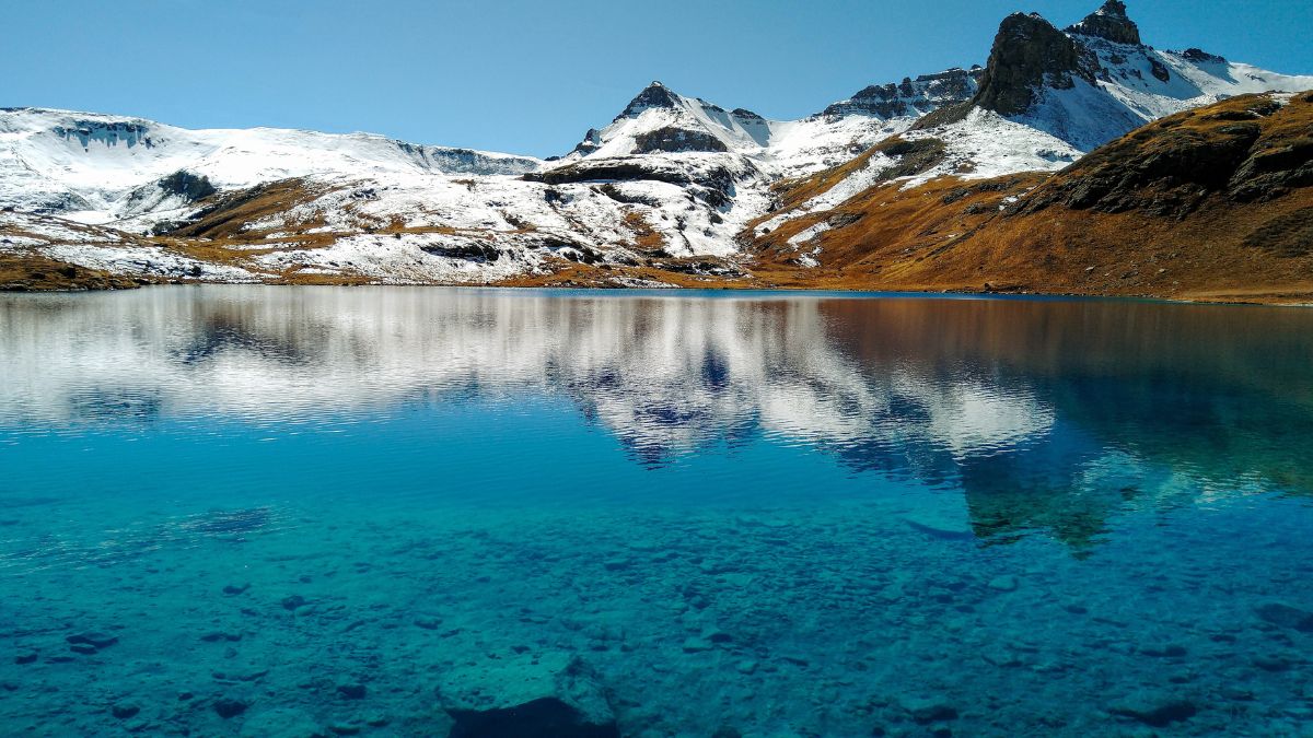 Ice Lake with clear water reflections and snow-covered mountain in background | San Juan National Forest, Colorado, USA.