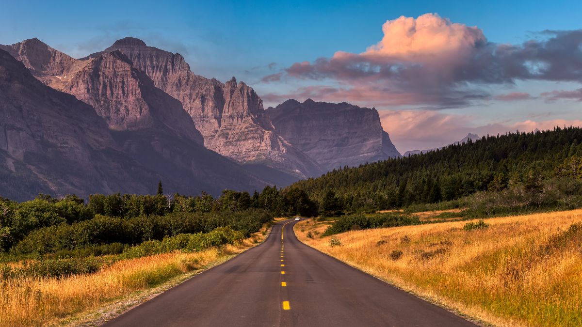 Beautiful View of Scenic Highway with American Rocky Mountain Landscape in the background. Colorful Summer Sunrise Sky. Taken in St Mary, Montana, United States.