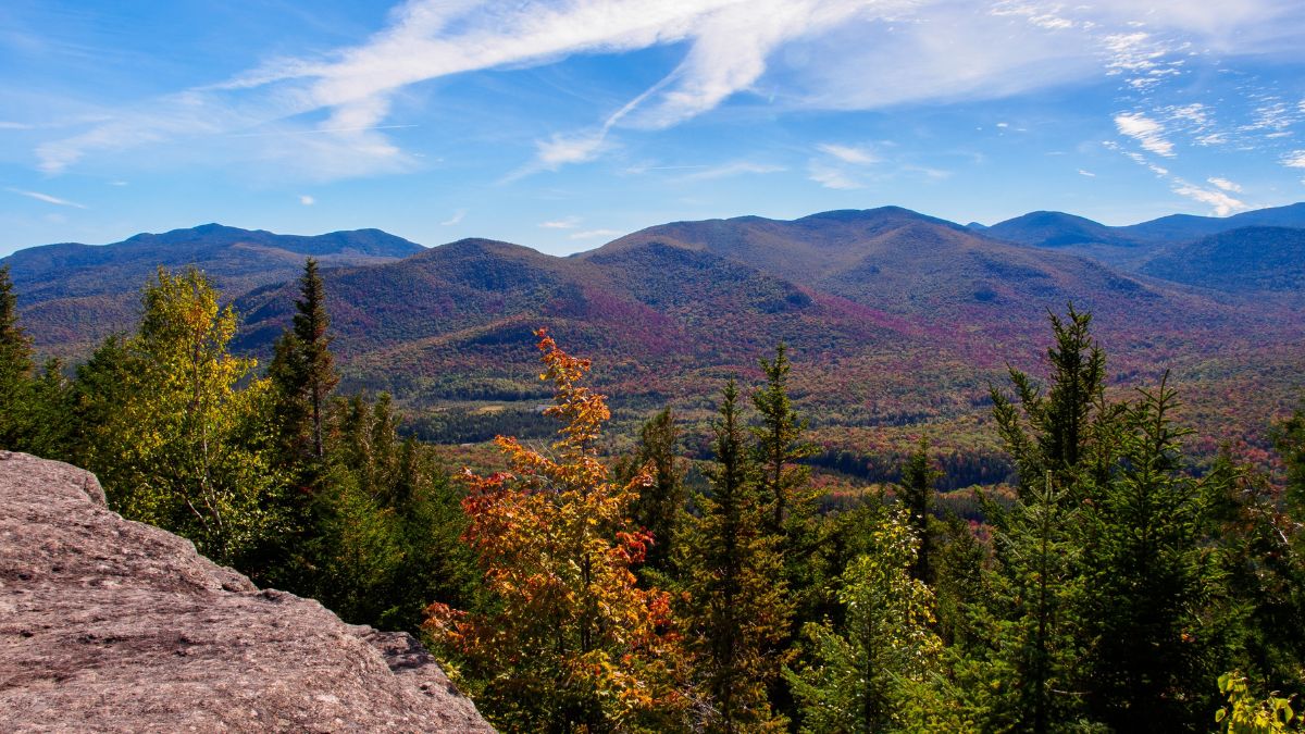 Breathtaking beauty of the Adirondack Mountains in New York State, where the landscape comes alive with the vibrant hues of fall colors against the backdrop of a stunning sky.