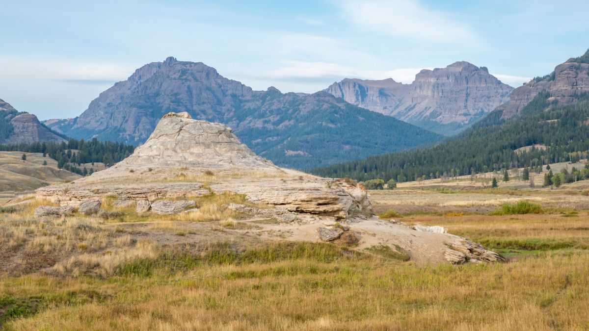Hot spring cone Soda Butte in Lamar Valley in Yellowstone National Park with valley and mountains in background.