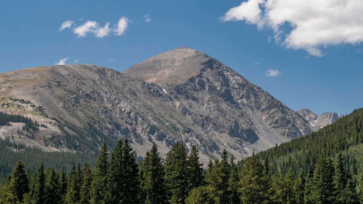 Quandary Peak in Colorado's Summit County is elegantly displayed against a beautiful blue sky on a warm summer day. The mountain rises 14,271 feet above sea level with its gentle slopes.