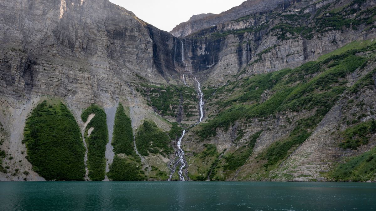 Snow Melt From Dixon Glacier Falls Into Lake Frances In Glacier National Park.