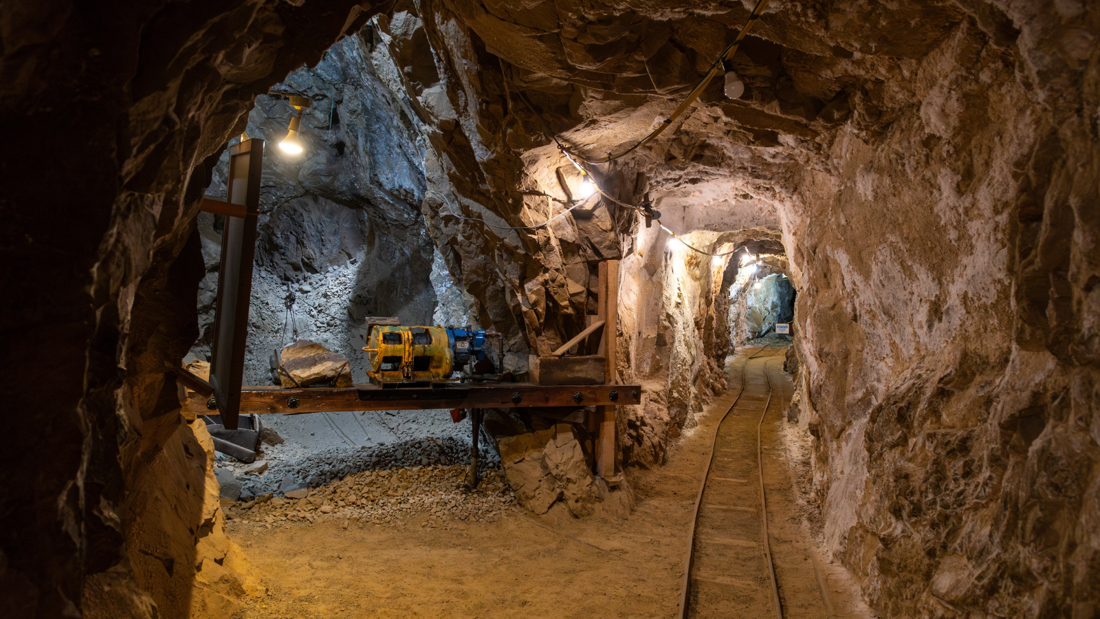 Exploring an abandoned underground mine in the mountains with machinery and tracks.