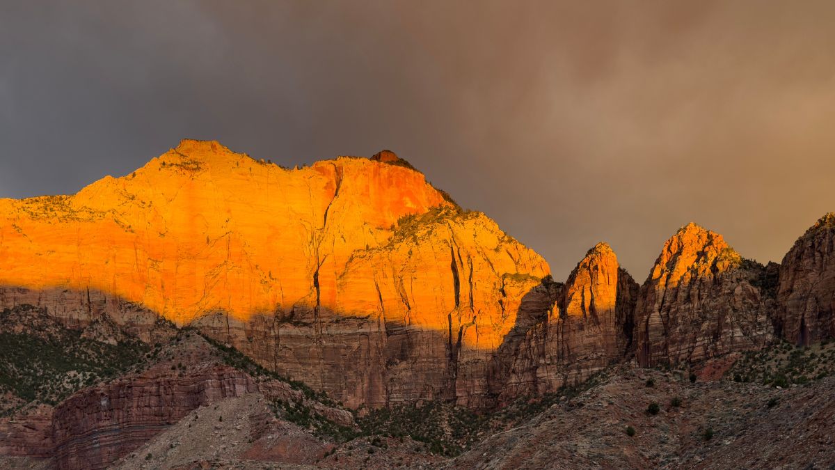 The light from a rising sun shines on West Temple at Zion National Park, Utah.