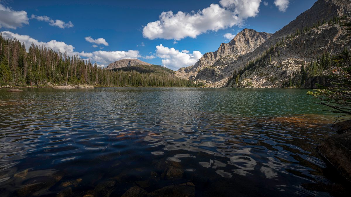 Water ripple at Lake Nanita, a high elevation alpine lake surrounded by pine trees and rocky mountains.