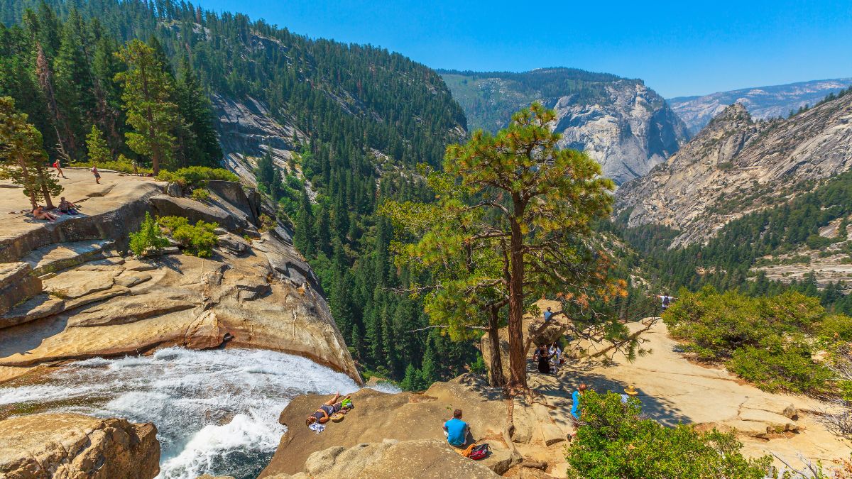 Yosemite, California, United States - July 24, 2019: people resting on top of Nevada Fall waterfall on Merced River from Mist Trail in Yosemite National Park, in California, United States.