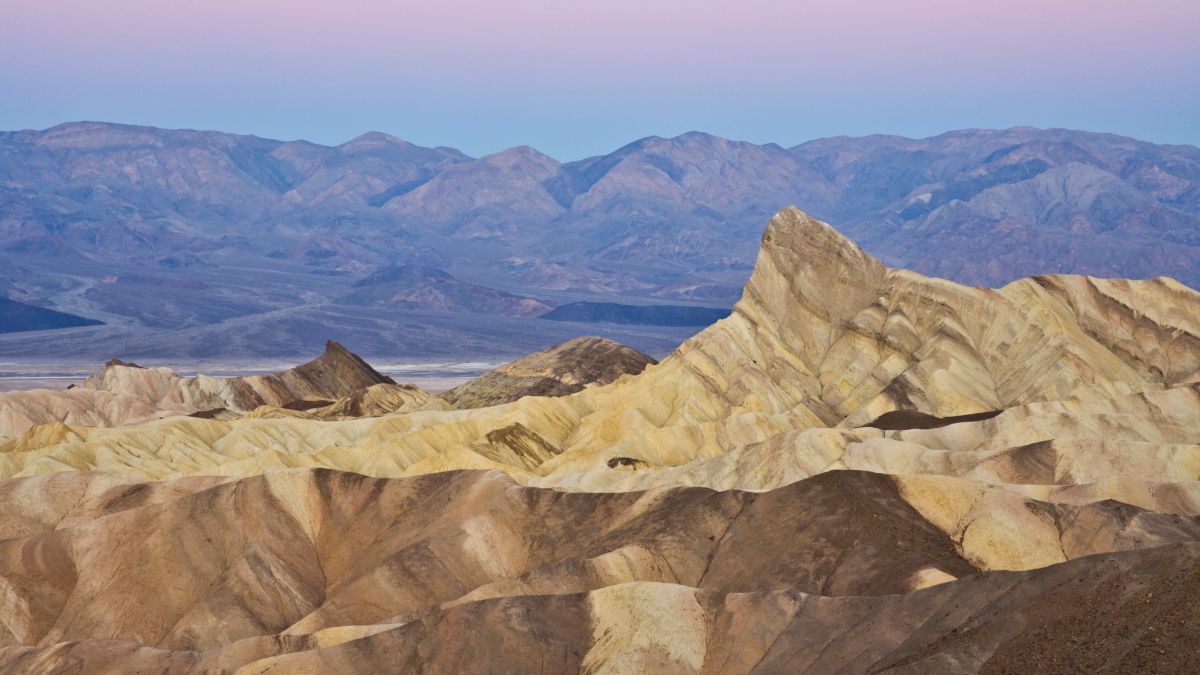 Manly beacon and the siltstone eroded foothills formations at zabriske point at sunrise, furnace creek, death valley national park, california, united states of america, north america.